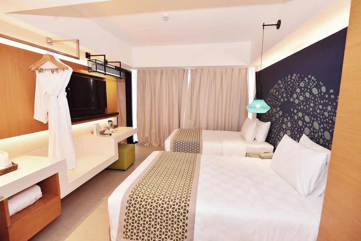 A hotel room with a bed, a sofa, a TV, a desk, and a bathroom area.