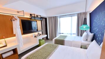 Habitación de hotel con dos camas, televisión, escritorio y ventana grande.