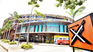 A modern building with a curved facade, outdoor seating area, and a vintage car parked in front. - Hue Hotels and Resorts Boracay Managed by HII (Boracay Island)