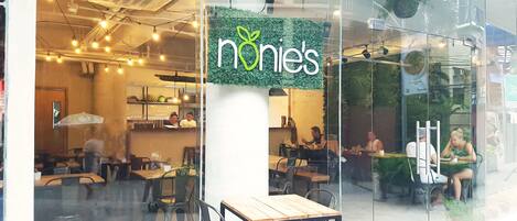 A restaurant with a glass facade, indoor seating, and a visible menu board.