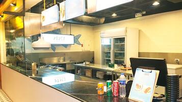 A kitchen area with stainless steel appliances, a sink, and a counter with a menu board.