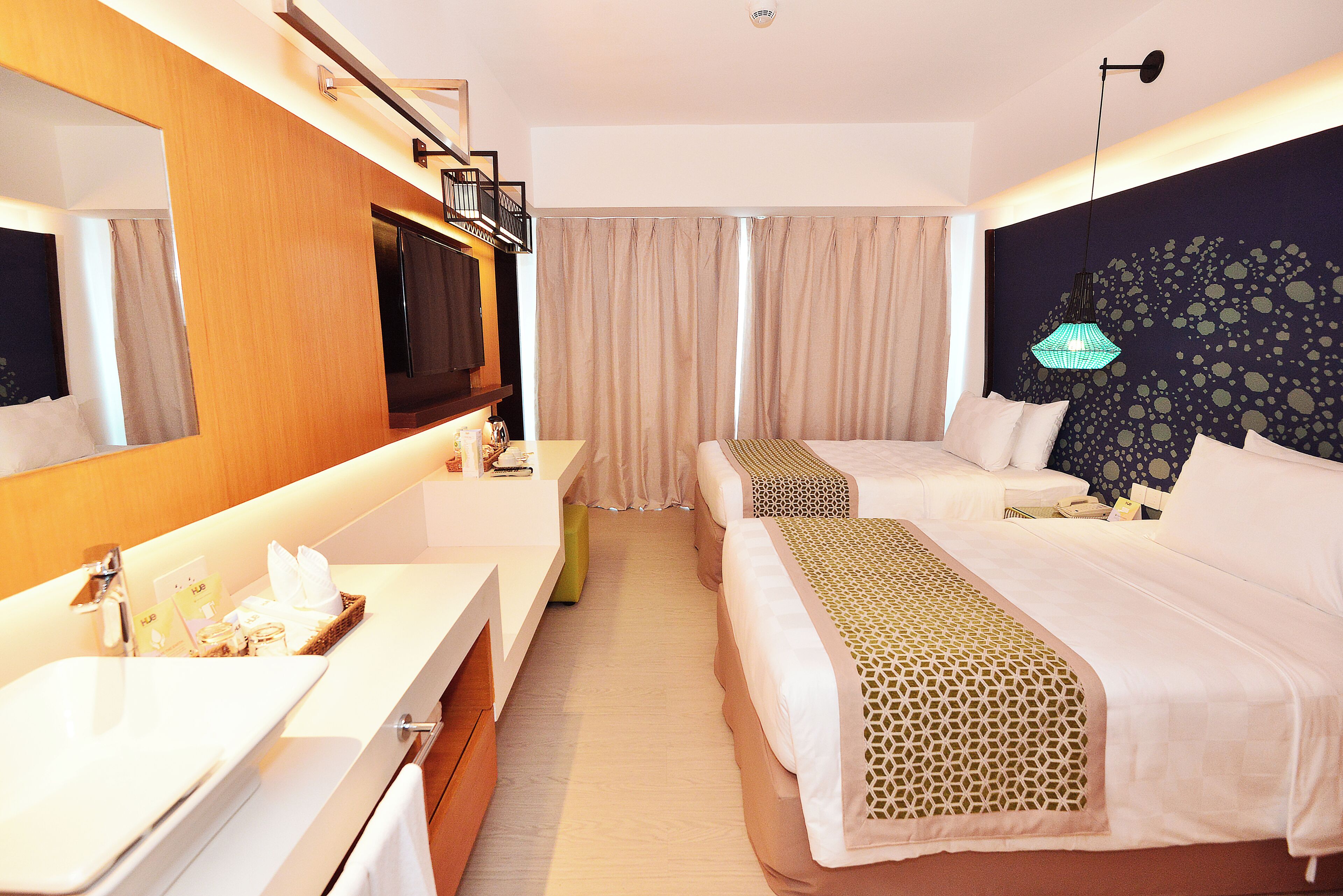 Ein Hotelzimmer mit einem großen Bett, einem Nachttisch, einem Spiegel, einem Fernseher und einem Badezimmer mit Waschbecken und Toilette.