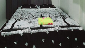Un dormitorio con una cama, aire acondicionado de pared y una cortina.