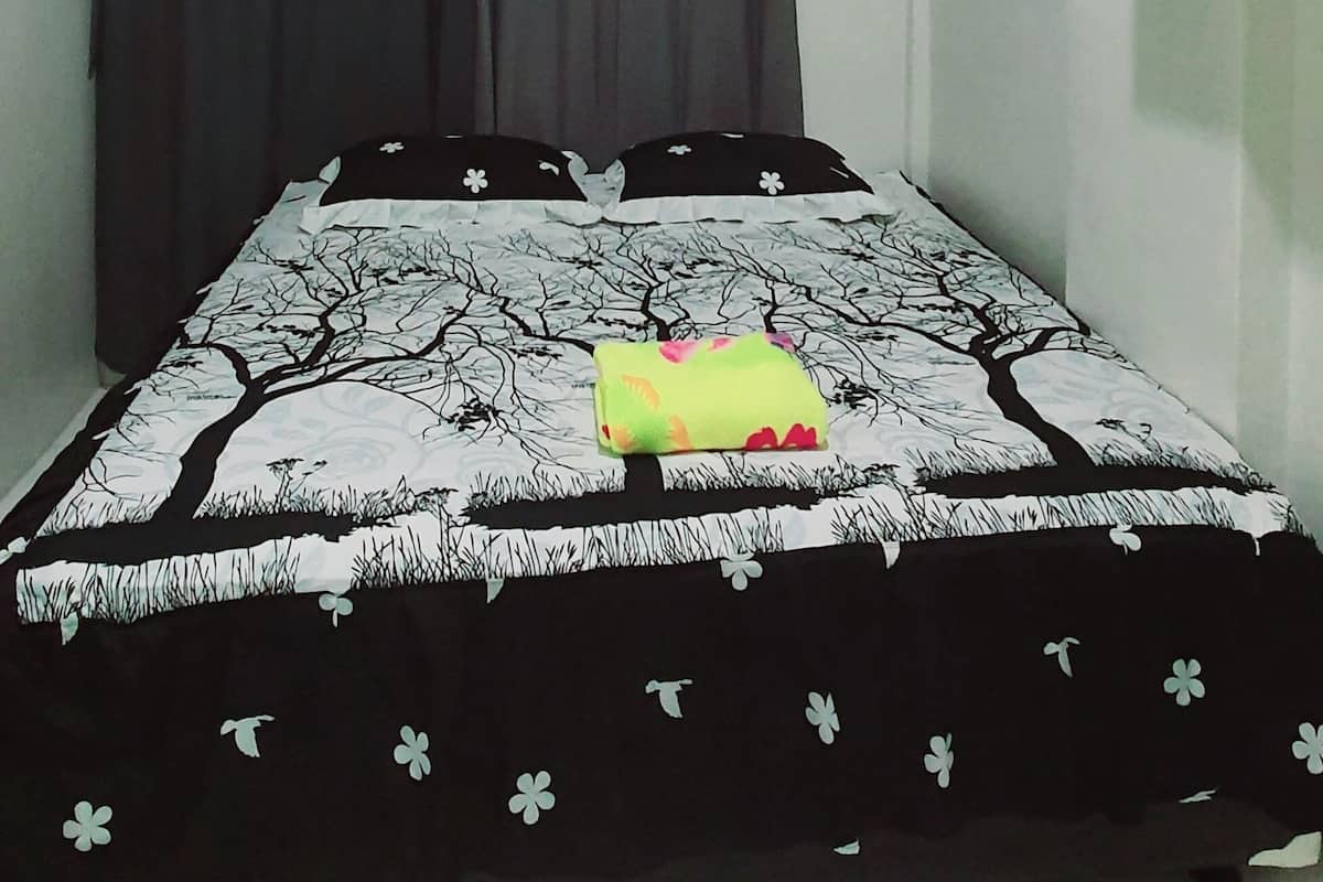 Ein Schlafzimmer mit Bett, Wandklimaanlage und Vorhang.