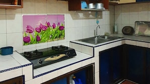 Una cocina con armarios de madera, salpicadero de azulejos, estufa a gas y un fregadero.