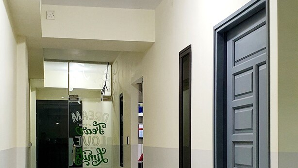 Un pasillo con suelo de baldosas, un felpudo verde en la entrada y una puerta con ventanal.