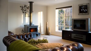 Una sala de estar moderna con un sofá de cuero, chimenea, televisor y un ventanal grande.