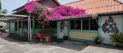 A building with a green and beige facade, a tiled roof, and a map mural on the wall.