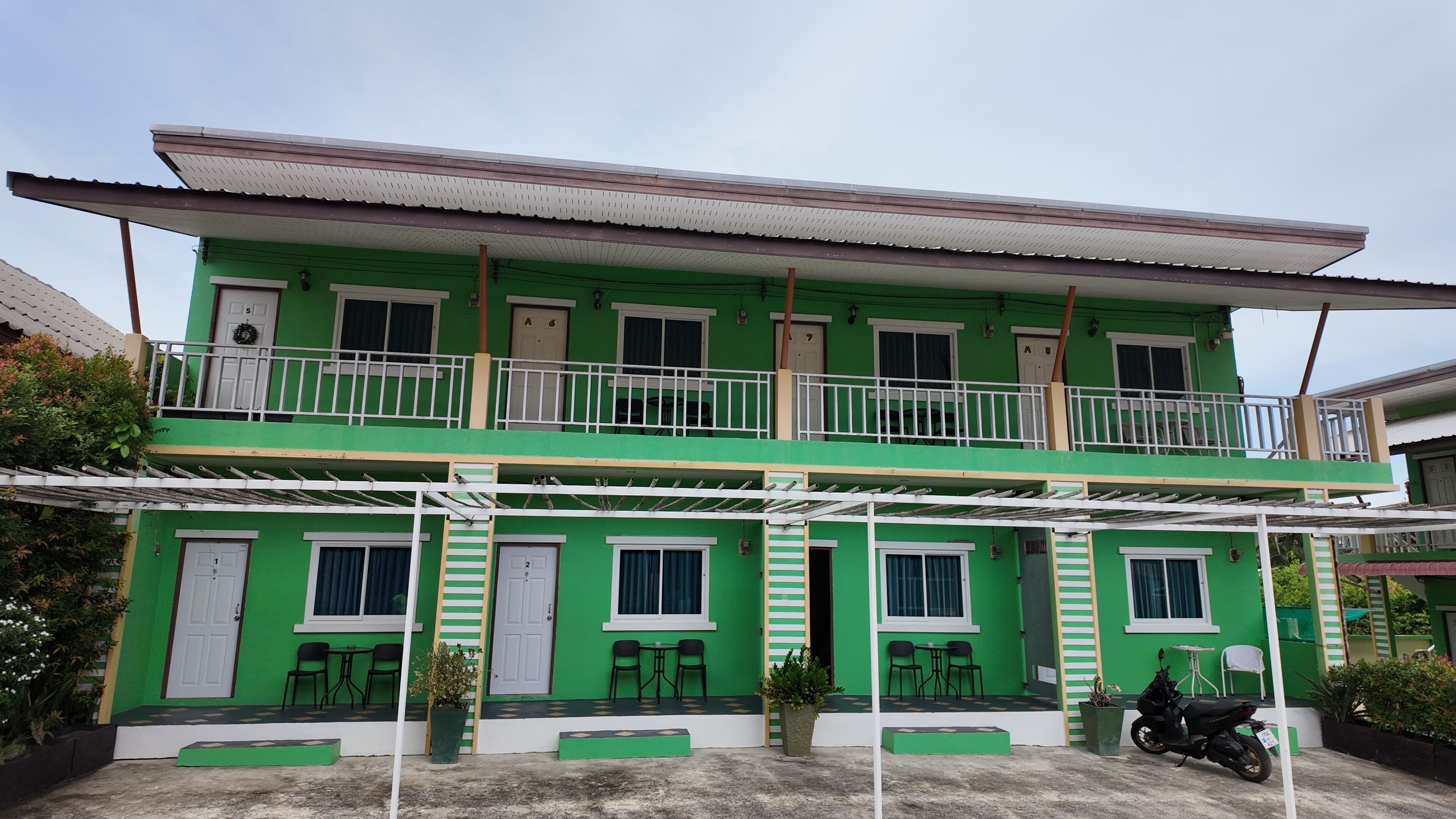 A two-story building with a green facade, multiple windows, and a balcony.