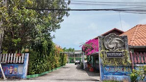 Un camino que lleva a un edificio con un letrero que dice 'VII HOUSE RAWAI PHUKET'.
