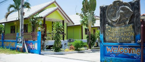 A colorful building with a sign welcoming visitors to V. Hemtanon Muay Thai.
