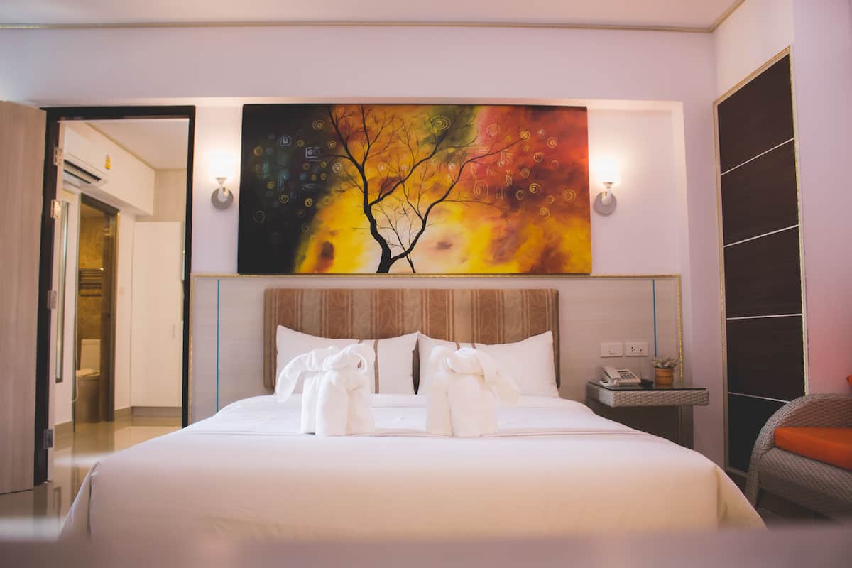 Une chambre d’hôtel avec un grand lit, un tableau au-dessus du lit et une table de chevet avec un téléphone et un vase.