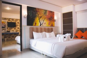 A modern hotel room with a large bed, a flat-screen TV, and a painting on the wall.