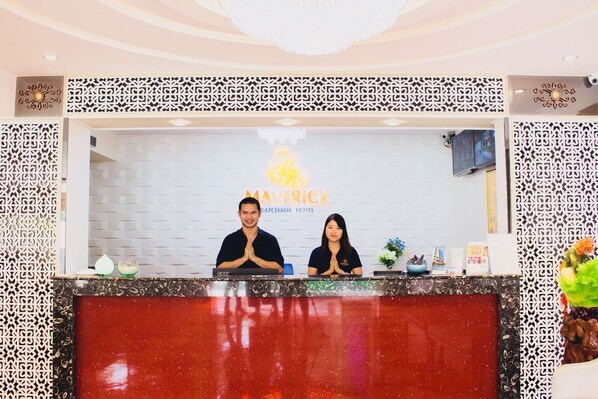 A reception desk at the Mavrick Ratchada Hotel with a modern design, featuring a red countertop and decorative panels.