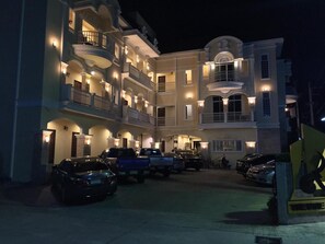 A multi-story hotel with balconies and a parking area.