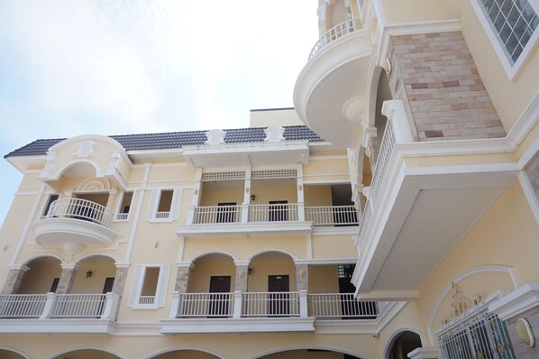 A multi-story building with balconies, arched windows, and a tiled roof.