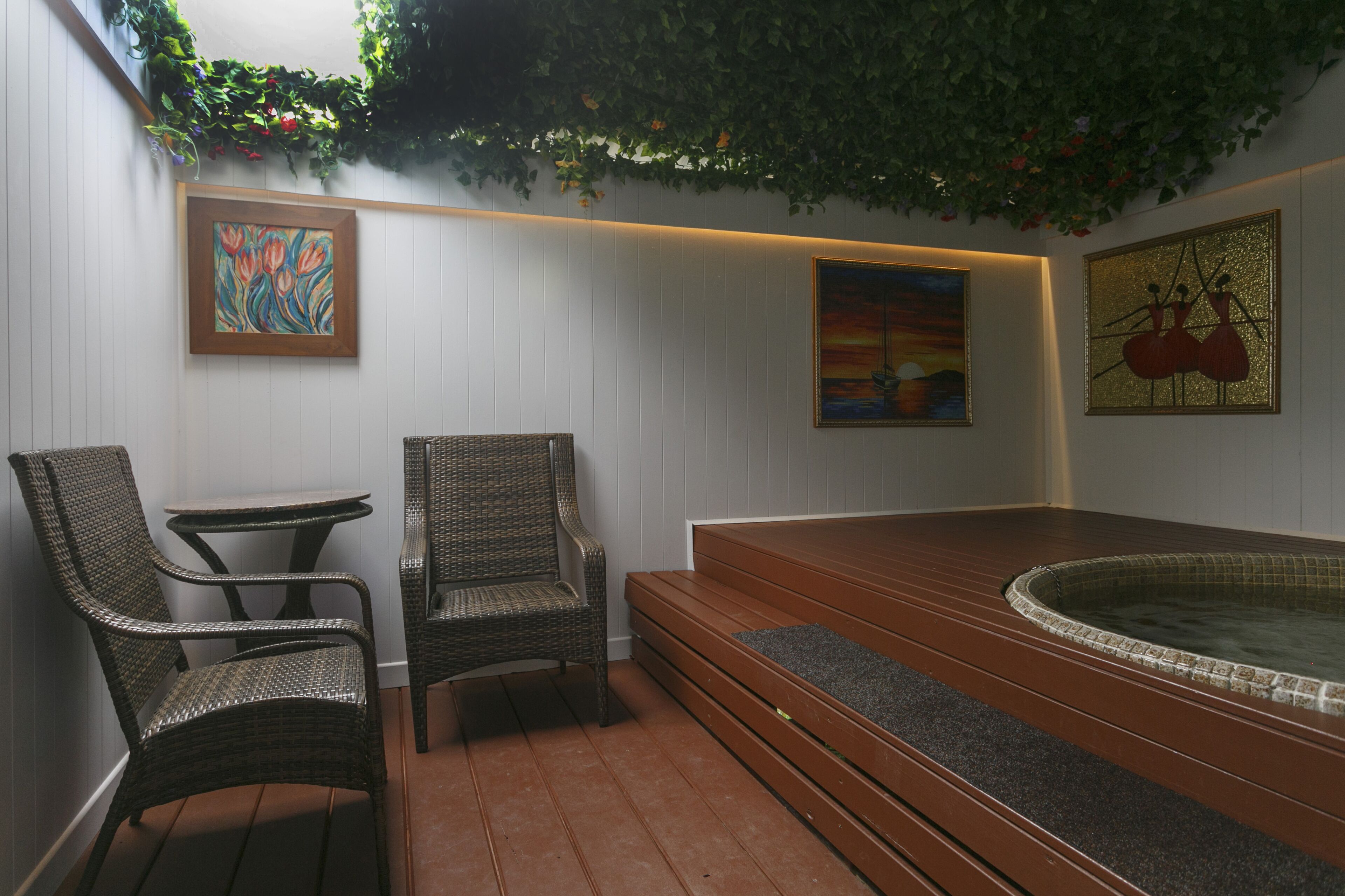 A spa area with wicker chairs, a small table, and a hot tub.