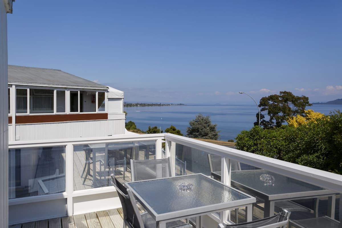 Un bâtiment moderne doté d’une terrasse vitrée offrant une vue sur une étendue d’eau.