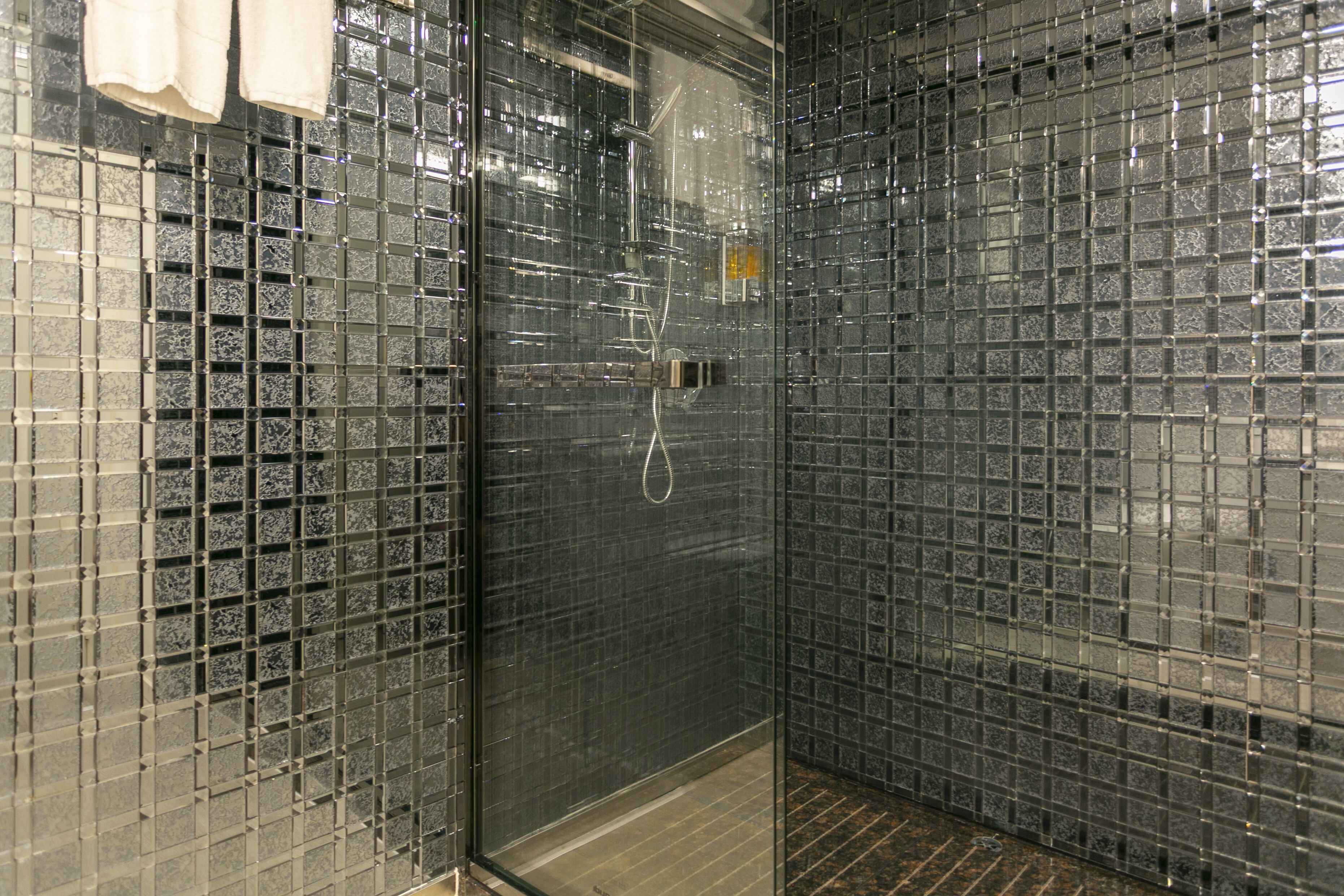 A glass-enclosed shower with a tiled wall.