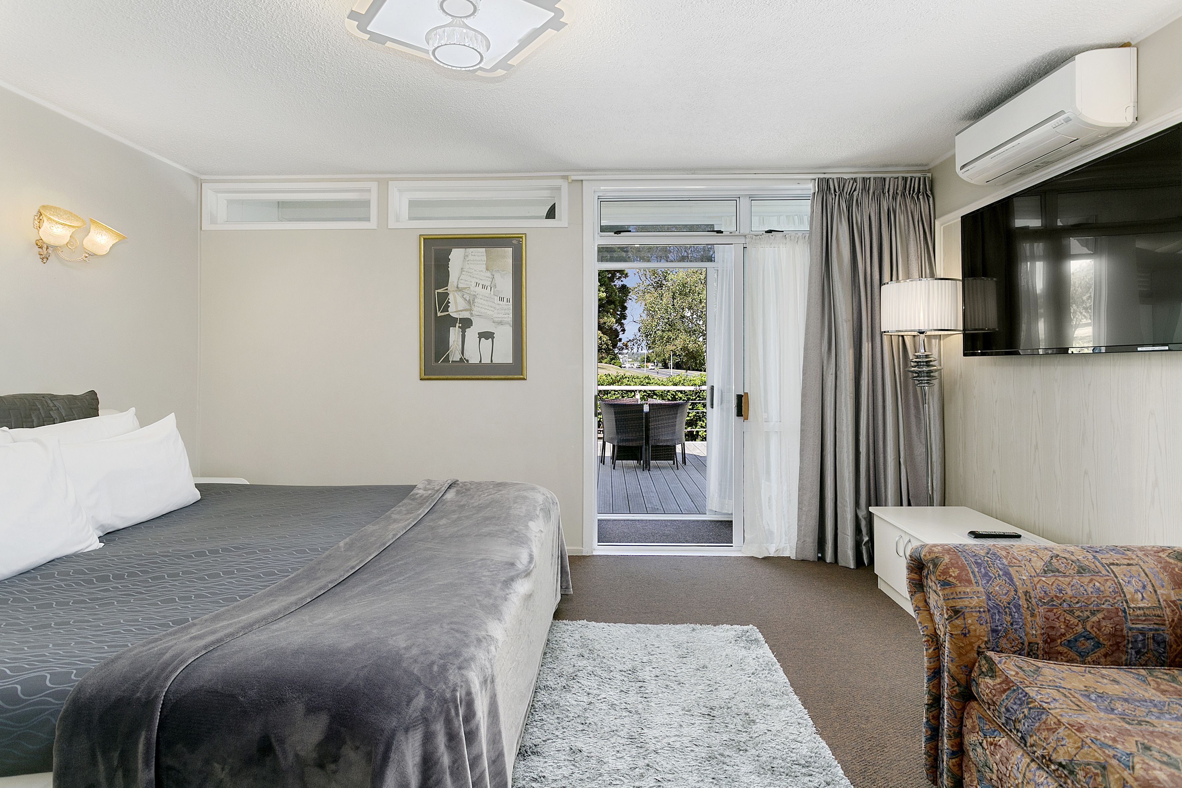 Ein Hotelzimmer mit Bett, einer Couch, einem Fernseher und Blick ins Freie.