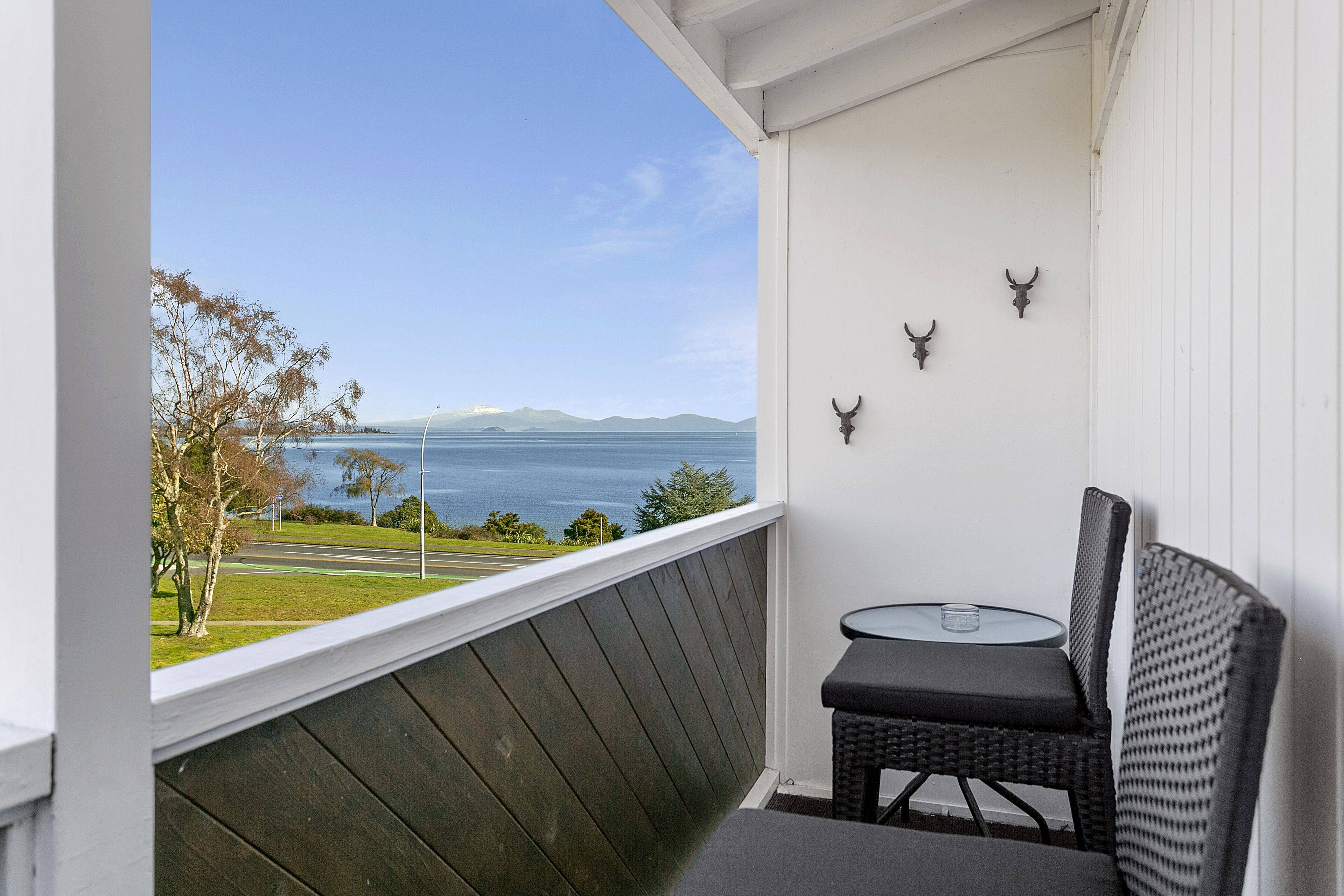 Een balkon met uitzicht op zee en bergen, een klein tafeltje en twee stoelen.