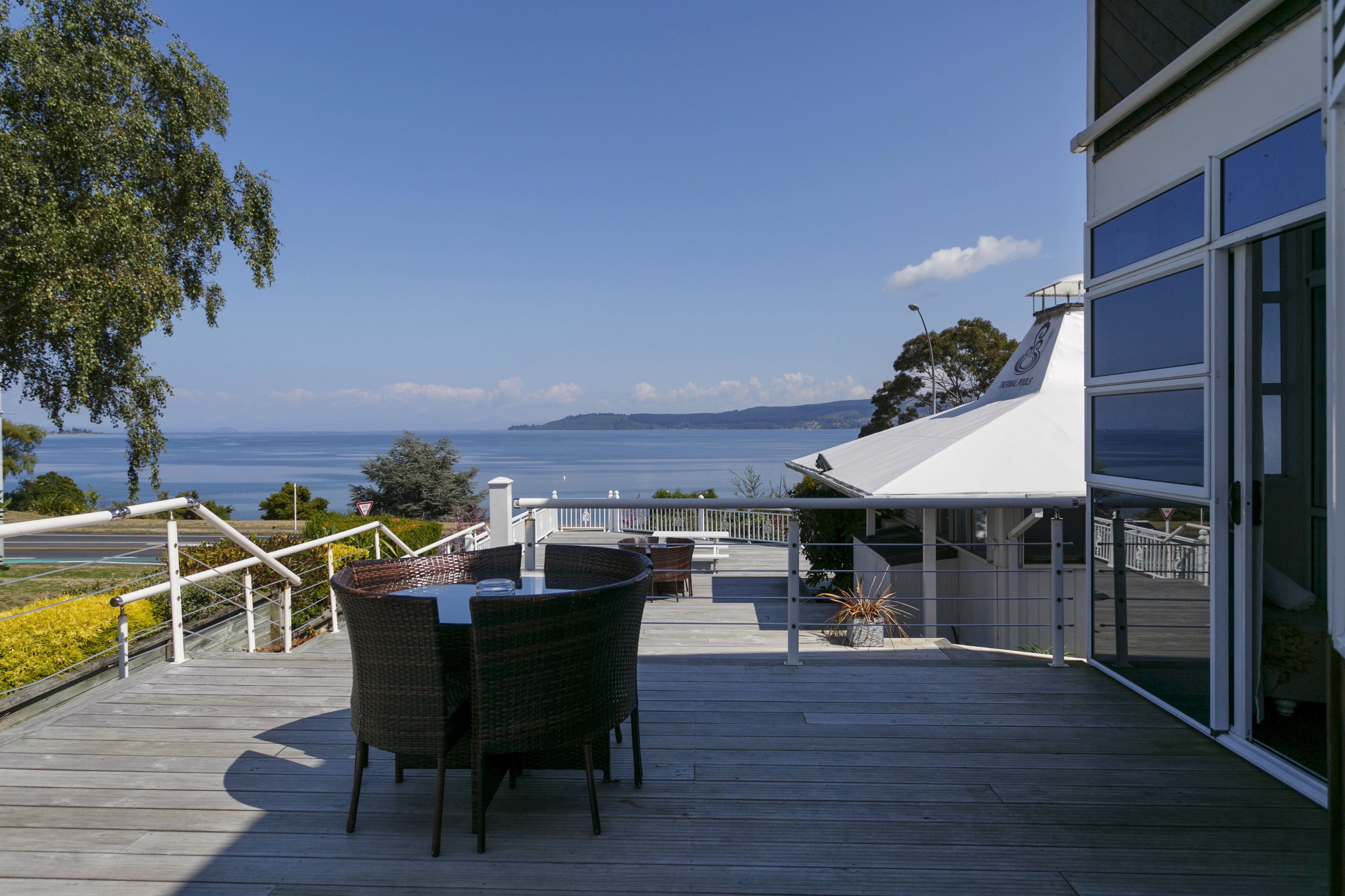 A wooden deck with a table and chairs overlooking a body of water.