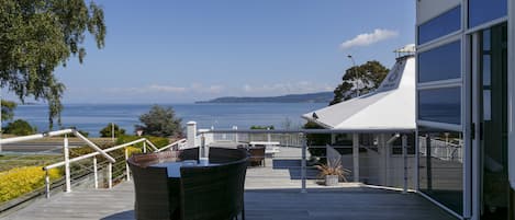 A wooden deck with a table and chairs overlooking a body of water.