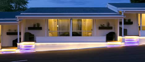 A row of white buildings with large windows and a covered porch area.