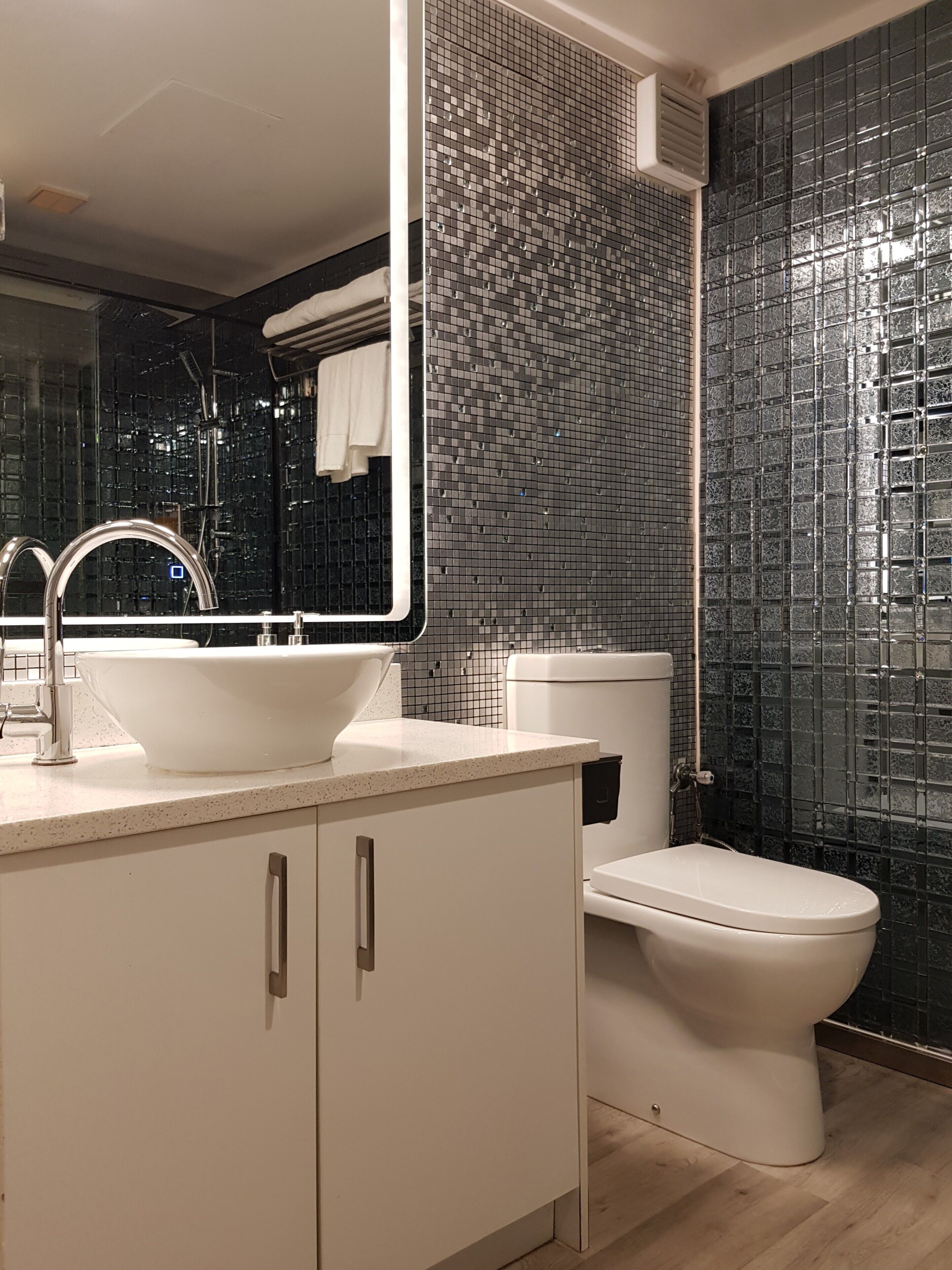 A modern bathroom with a white sink, mirror, and toilet.