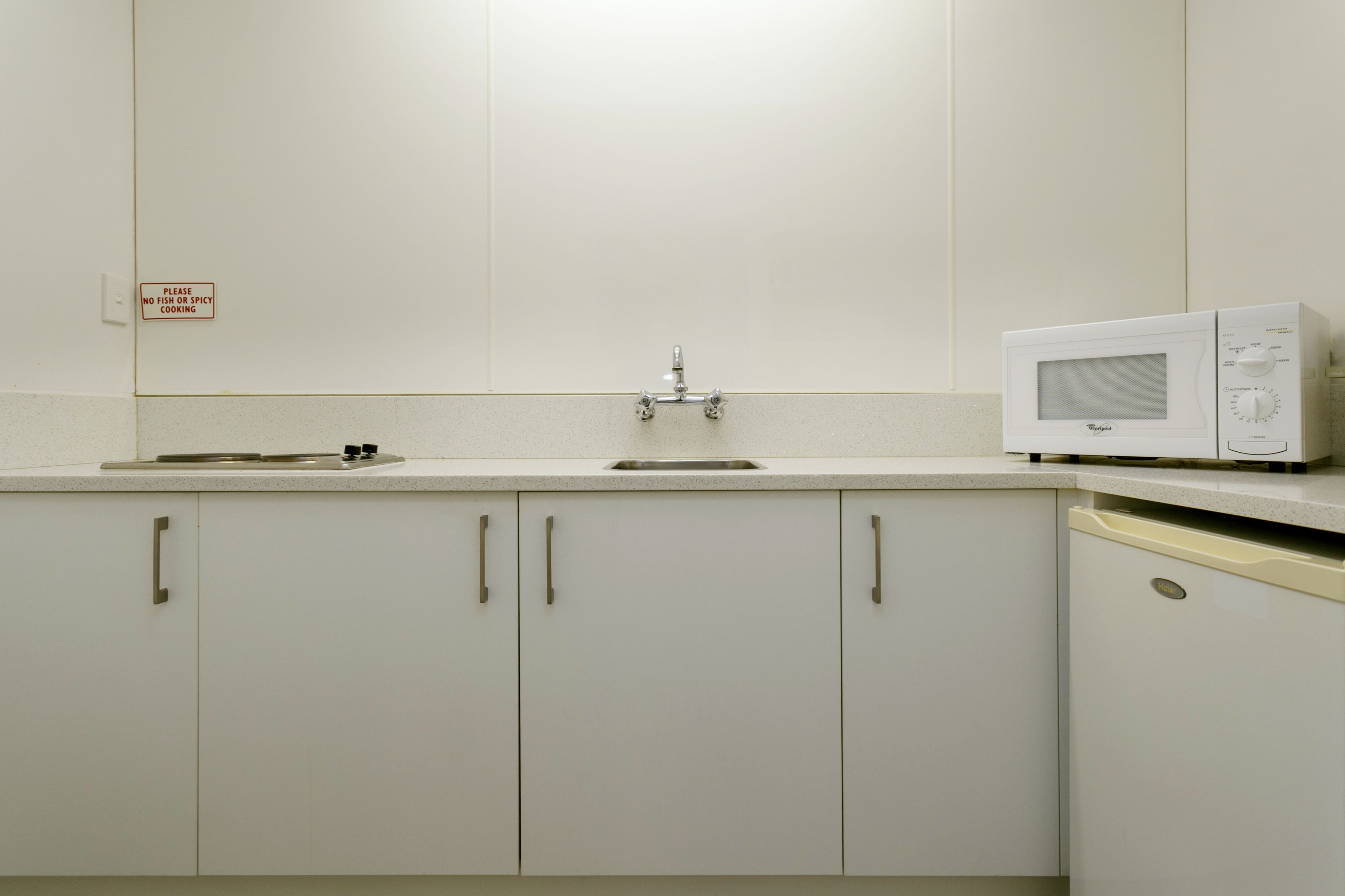 Une cuisine avec des meubles blancs, un four à micro-ondes et un évier.