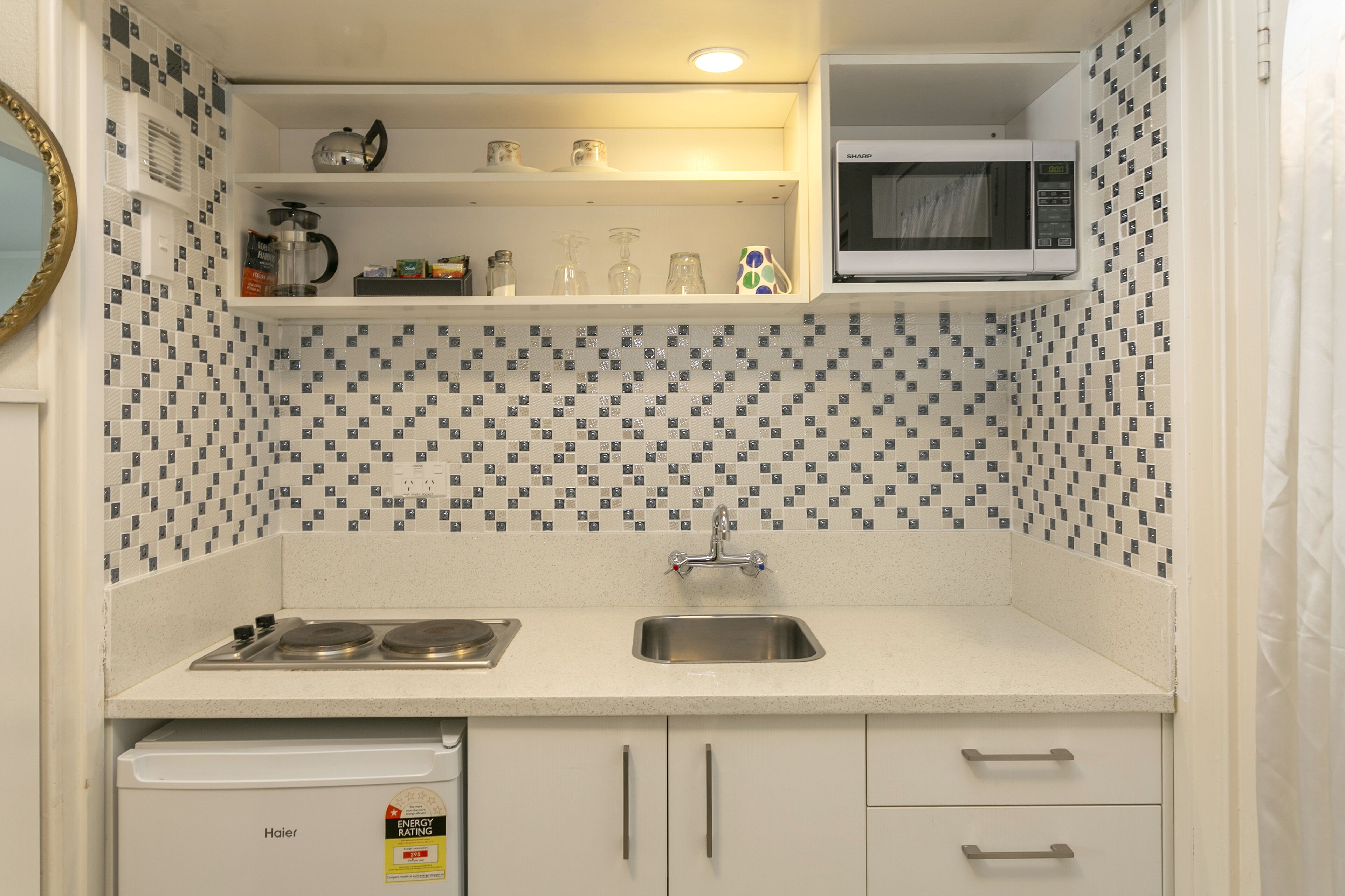 Una cocina compacta equipada con microondas, lavaplatos y fregadero.