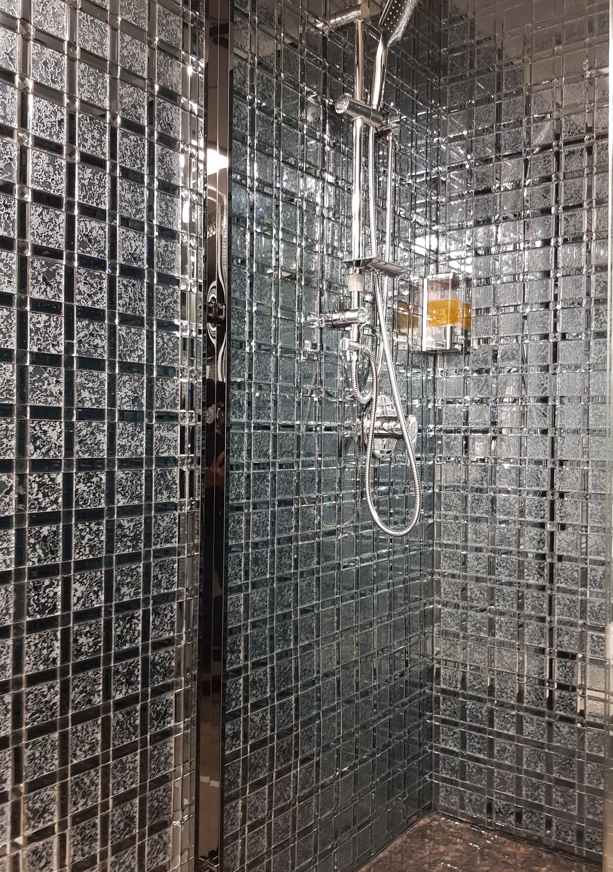 A shower area with a glass block wall and a handheld showerhead.