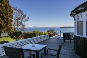 Une terrasse avec une table et des chaises, d’où l’on peut admirer un plan d’eau et, au loin, des montagnes.