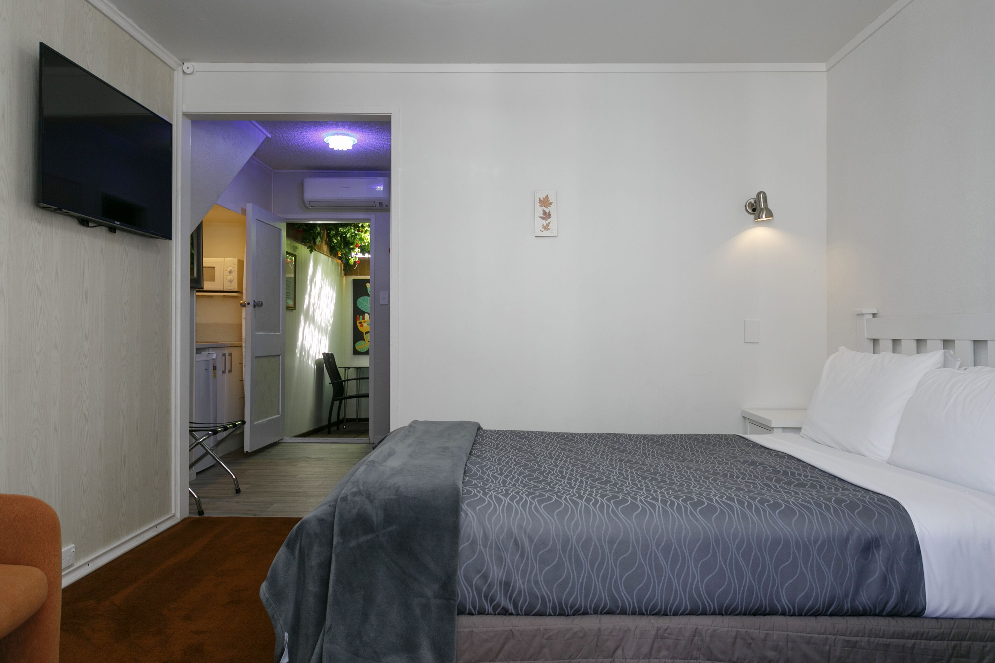 A bedroom with a bed, a TV, and a door leading to a bathroom.