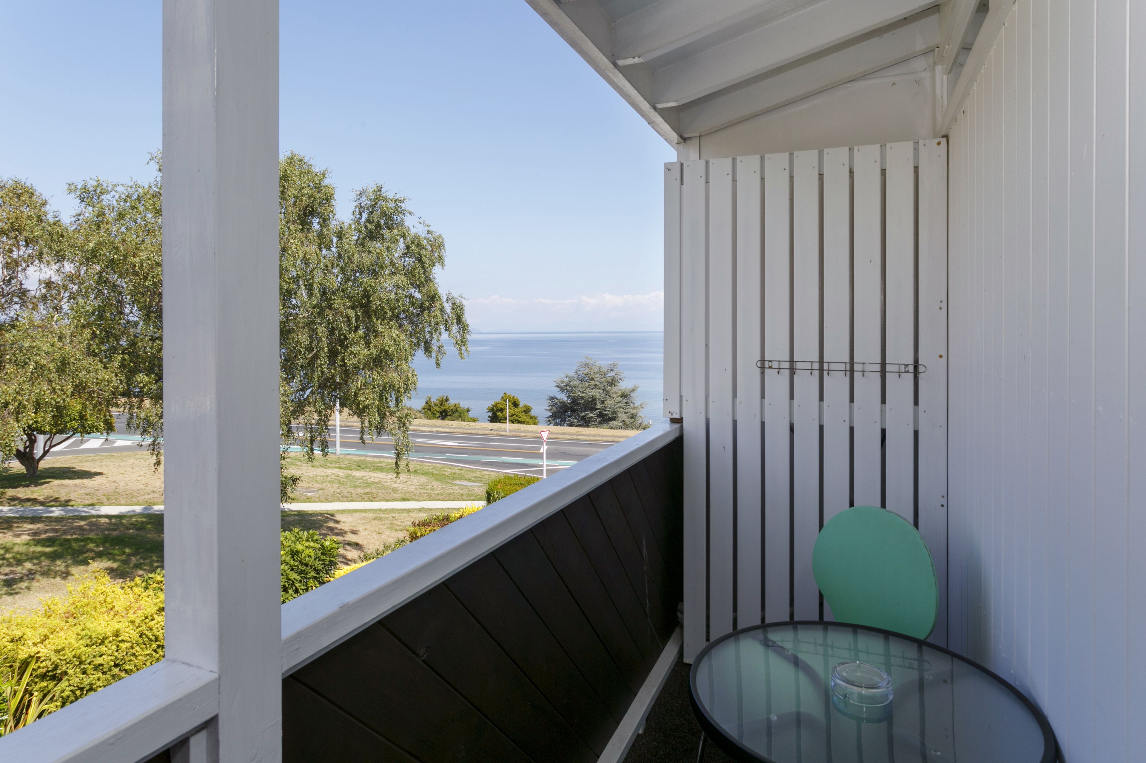 A balcony with a clear view of the sea and a road.