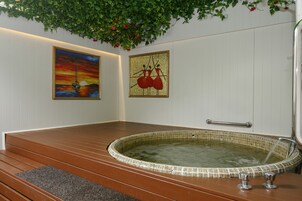 Un cuarto de spa con un banco de madera, una bañera de hidromasaje y dos obras de arte enmarcadas en la pared.