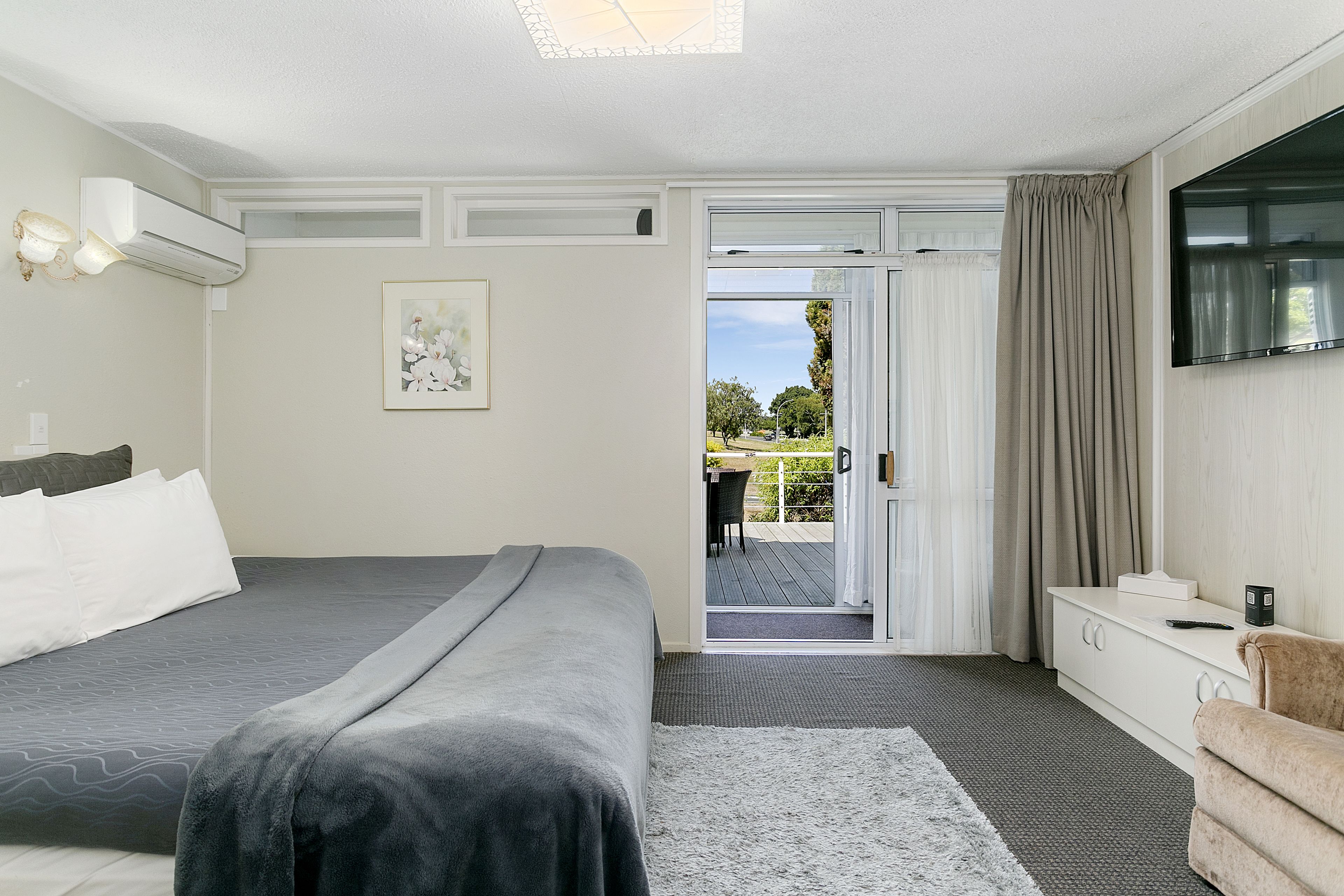 A bedroom with a bed, a desk, a chair, and a TV.