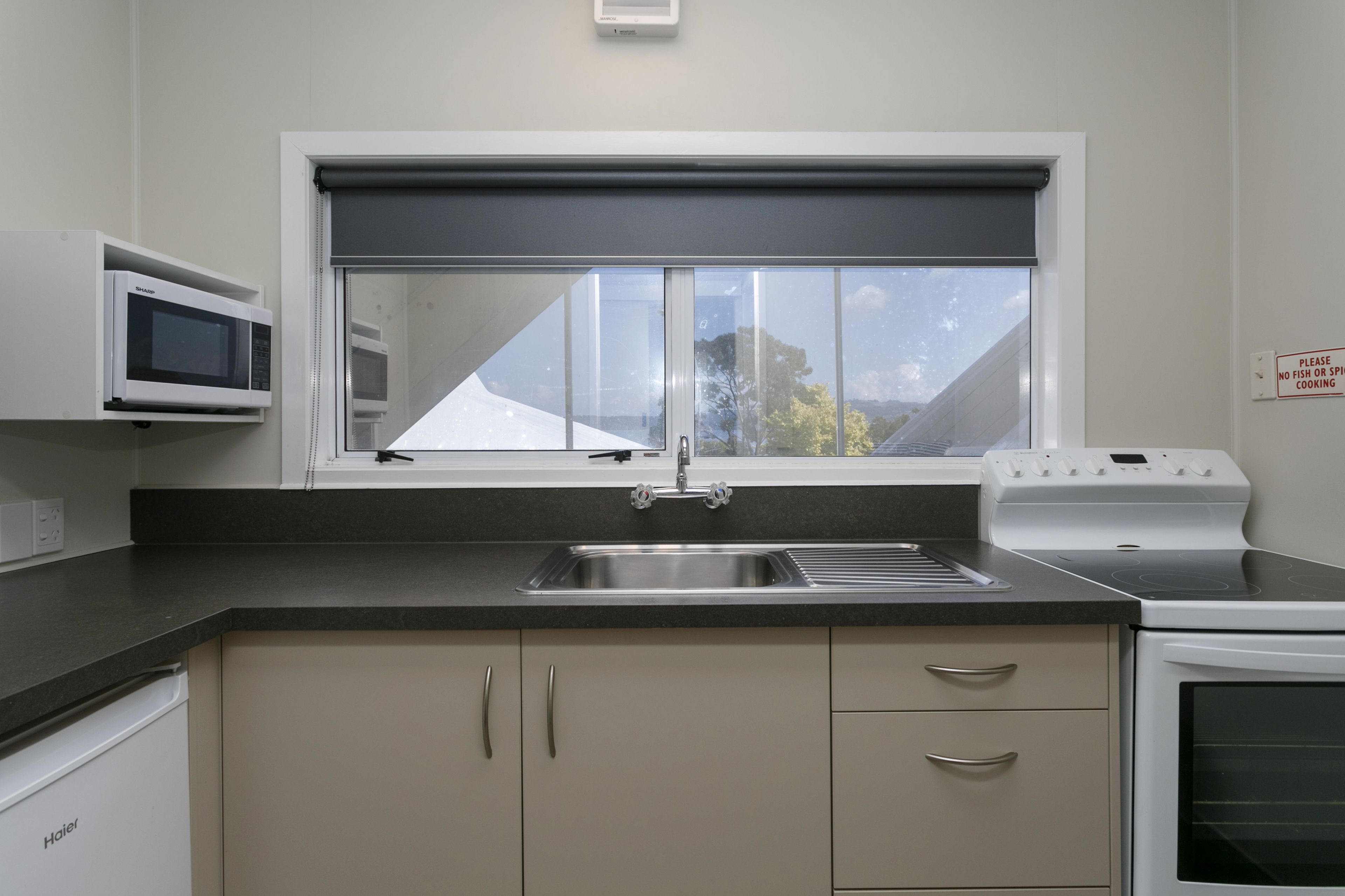 A kitchen with a window, a microwave, a stove, and a sink.