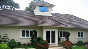 A two-story house with a brown roof, beige walls, and a front entrance with a set of steps. - Pattaya Longstay Village 3 (Bang Lamung)