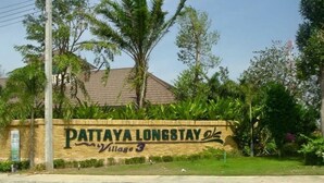 A sign for Pattaya Longstay Village 3 with a paved walkway in front. - Pattaya Longstay Village 3 (Bang Lamung)