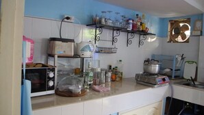 Una cocina con armarios blancos, un microondas, una cafetera y varios utensilios de cocina sobre la encimera.