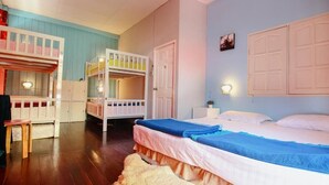 Una habitación con literas, un escritorio y una cama con una manta azul.