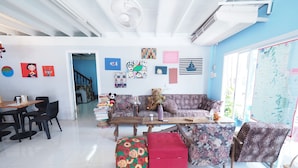 Una sala de estar con sofá, reposapiés y mesa de centro, un comedor con sillas y una mesa, y una escalera que lleva a otro nivel.
