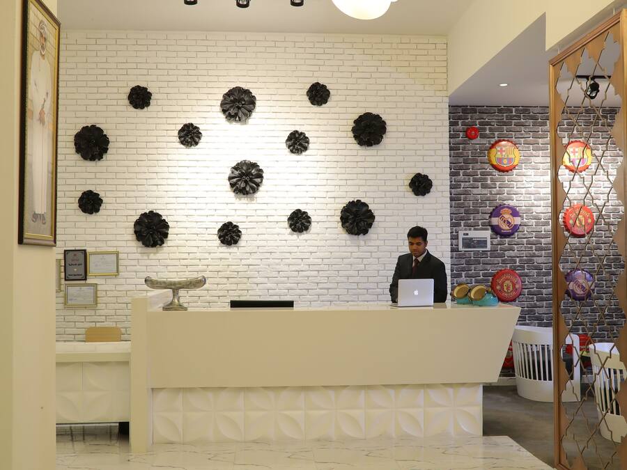 Una recepción con un mostrador blanco y una pared decorativa con motivos florales negros.