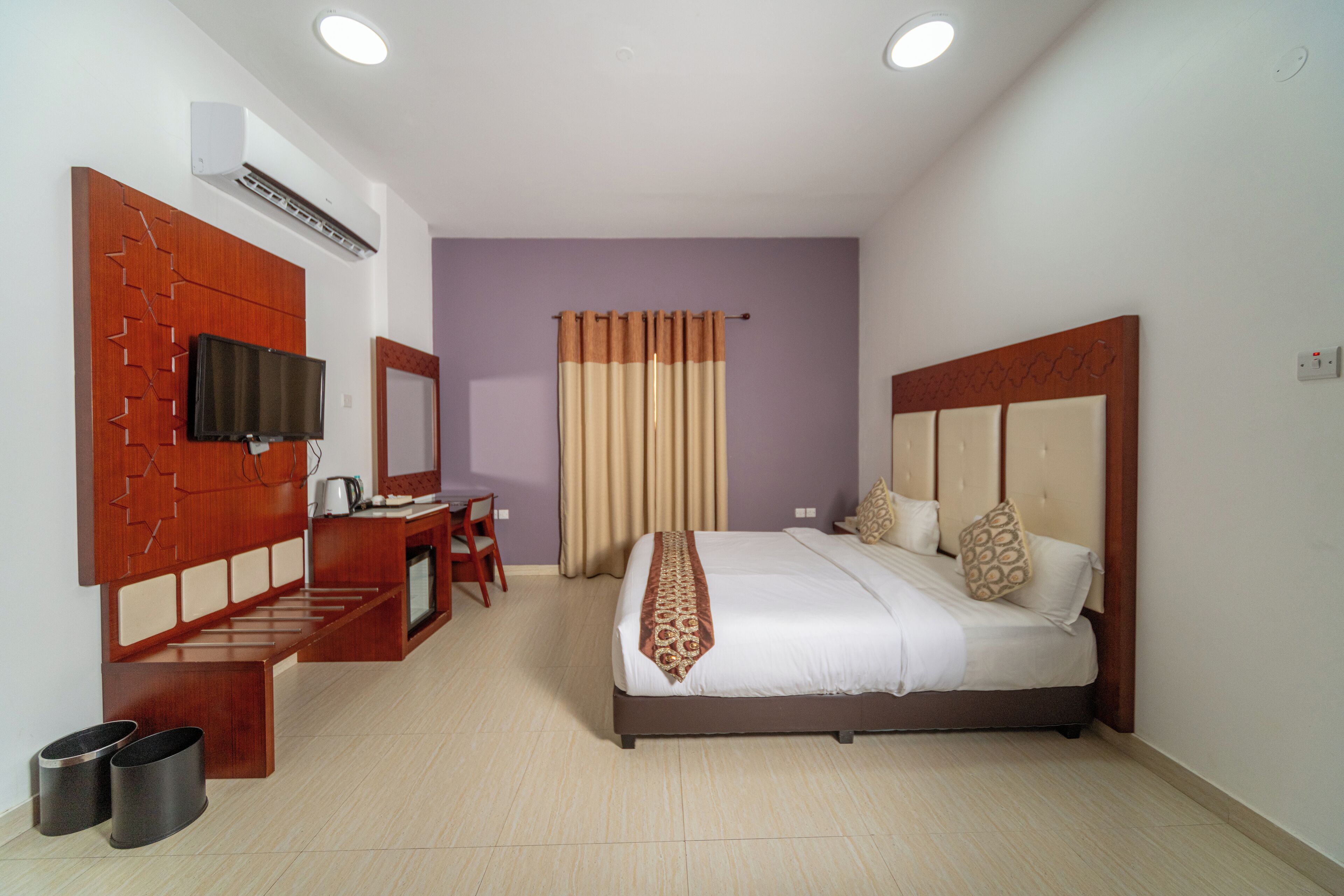 A hotel room with a bed, a desk with a chair, a television, and a bathroom.