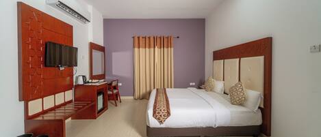 A hotel room with a bed, a desk with a chair, a television, and a bathroom.