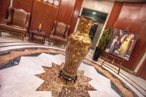 A lobby with a large ornate vase on a marble floor, surrounded by leather chairs and a painting on the wall. - Sofia Suites Hotel (Amman)