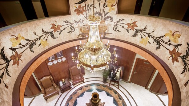 A grand lobby with a large chandelier, a central decorative vase, and a seating area with leather chairs. - Sofia Suites Hotel (Amman)