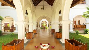 A spacious corridor with wooden benches and a central floral arrangement. - Le Pondy Beach & Lake Resort (Puducherry)