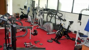 Un gimnasio con equipo de ejercicio diverso, incluyendo cintas de correr, bicicletas estáticas y máquinas de pesas.